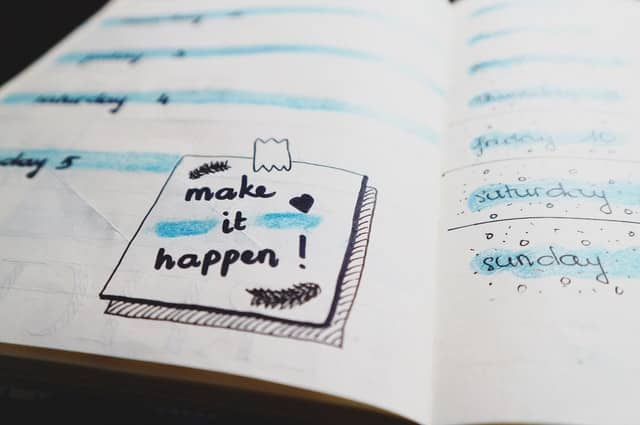 make it happen written on notebook highlighted with blue color