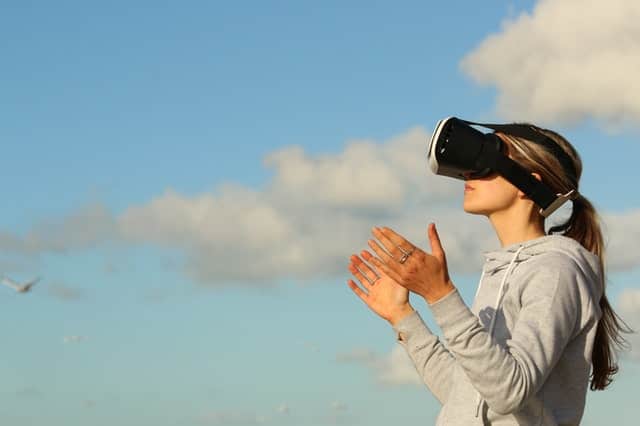 woman using VR with the sky and clouds behind her