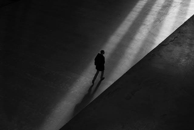 a guy in the darkness with his shadow behind him, walking towards the light. 