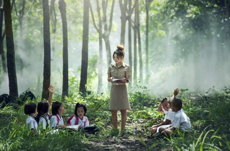 Asian teacher teaching students in forest