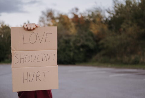 woman holding card box written love shouldn't hurt