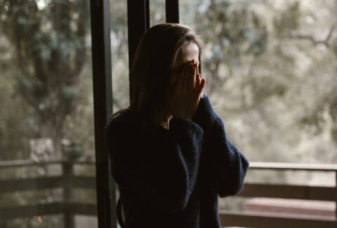 stressed girl covering her face with hands in prayer form-min