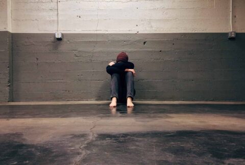 man sitting head down alone in the middle of the room