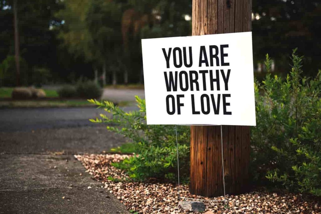 Sign on a tree in a forest saying you are worthy of love