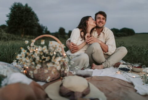 couple having picnic with basket of flowers in nature