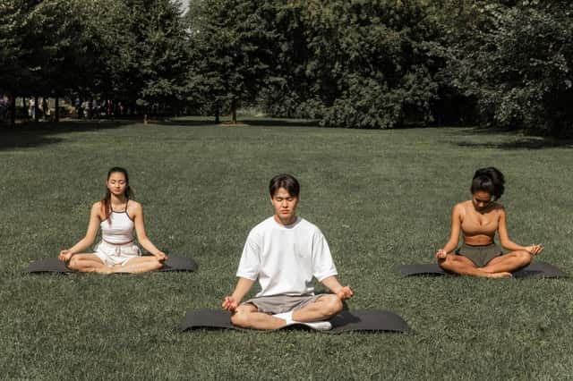 3 people meditating in nature surrender to the universe