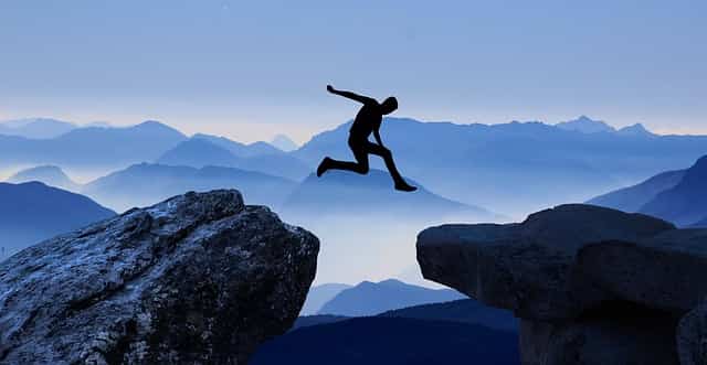 guy jumping from one cliff to another step out of comfort zone surrender to the universe