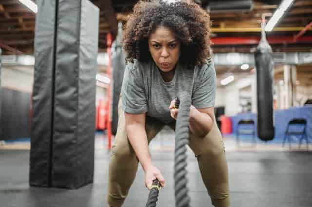 woman at the gym hitting the rope challenging herself out of her comfort zone