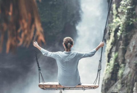 happiness is a state of mind girl on swing in nature looking at waterfall