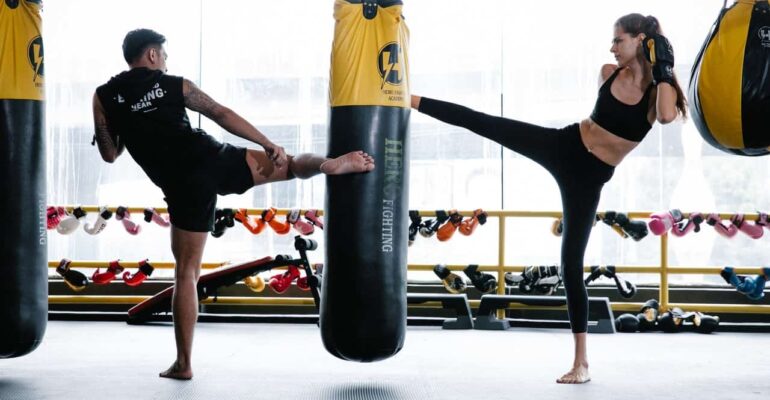 male and female doing kickboxing kicking punching bag