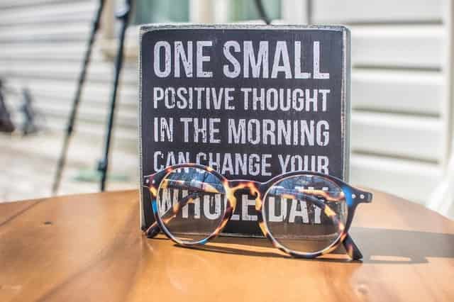 one small positive thought in the morning can change your life written on blackboard with glasses in front of it