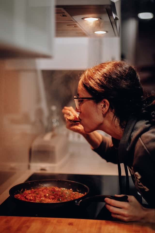 a woman cooking and tasting food while still on the electric hub