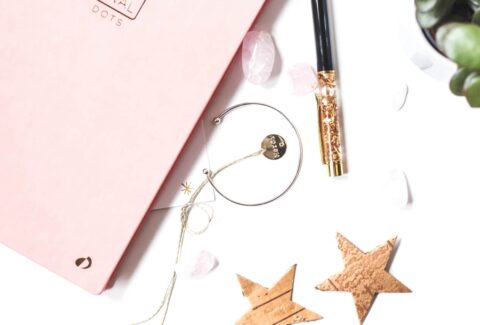 pink journal with gold stars, bracelet and glittery pen to manifest by writing
