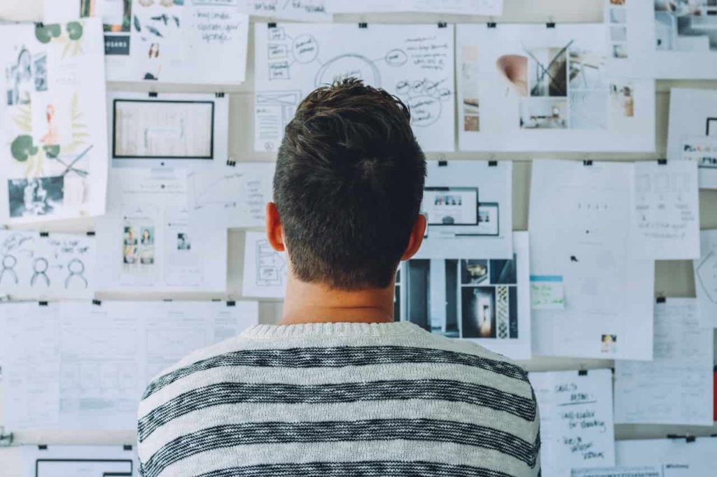 a guy looking at his vision board filled with roadmaps to pursue his dreams and achieve his goals