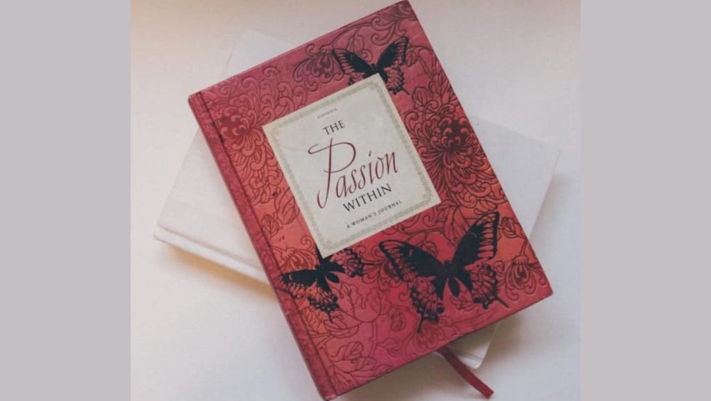 a red journal with beautiful black butterflies on it and the words written: "The passion within".