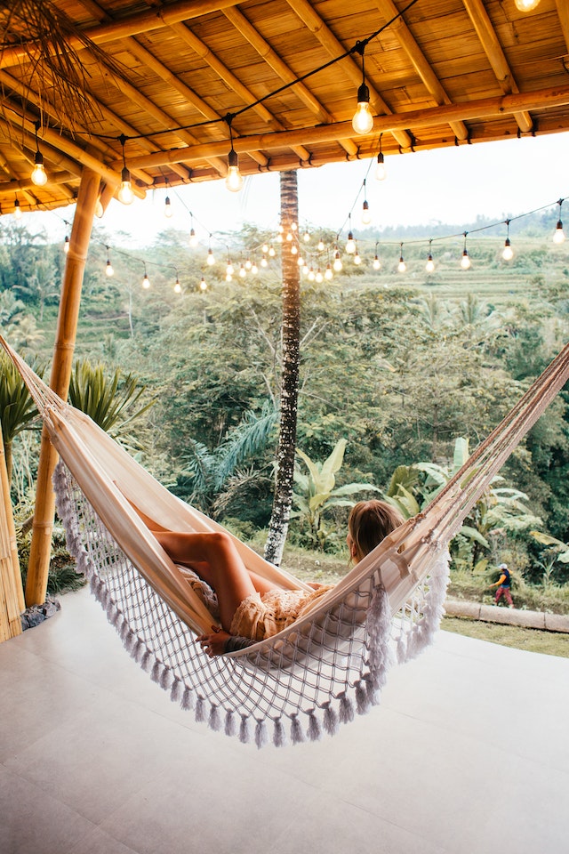 a girl on a hammock looking over at a beautiful green lush abundant jungle