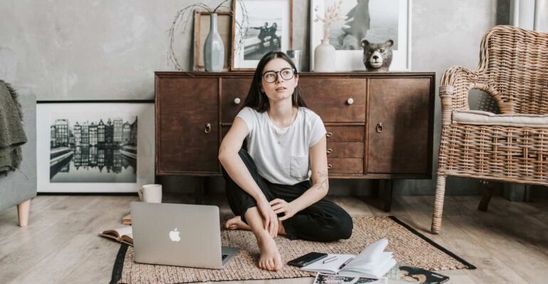 A woman on the floor with her laptop reflecting on how to break codependency