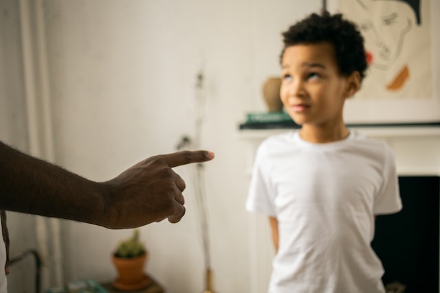 A critical parent pointing index finger at his son 