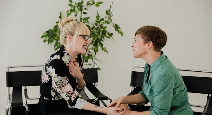 a woman speaking with her spiritual mentor smiling and holding hands in the office