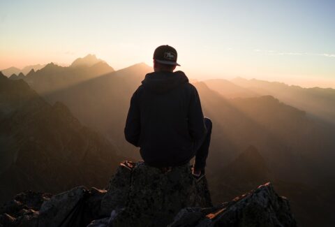 a guy on top of mountains looking at other mountains in silhouette pondering how to discover his life purpose