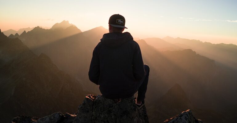 a guy on top of mountains looking at other mountains in silhouette pondering how to discover his life purpose