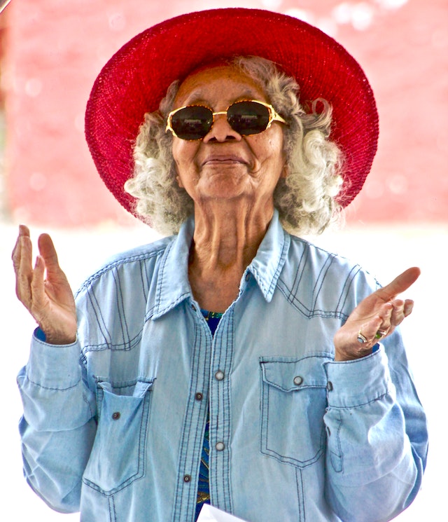 a woman finding purpose in life after 50 rediscovering her passions wearing a red hat cool sunglasses and vintage denim shirt looking swag