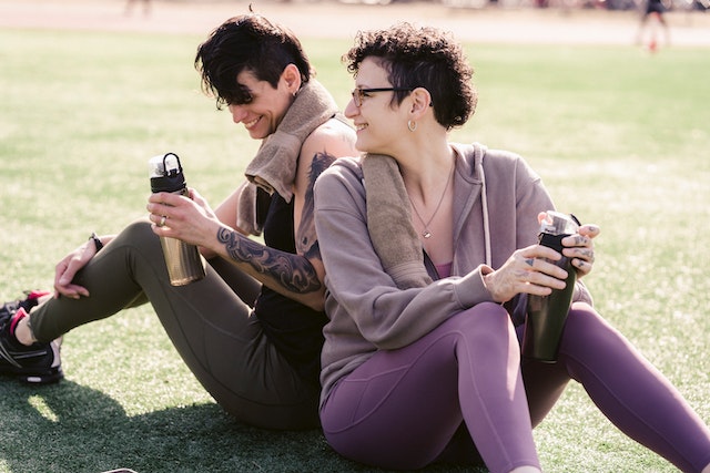 two women sitting on the ground smiling at each other practicing healthy communication and emotional intelligence in relationships