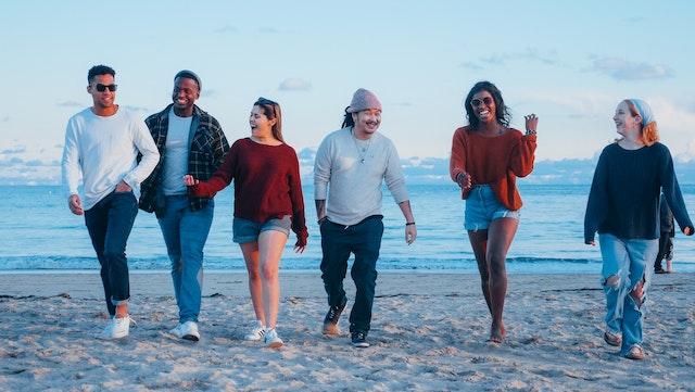 socially aware group of friends smiling and walking together on the beach demonstrating high emotional intelligence