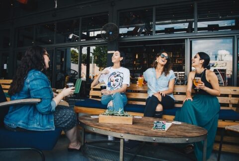 a group of friends sitting down together having lunch on a bench in a restaurant demonstrating social awareness and emotional intelligence by displaying different emotions like smiling, laughing and talking