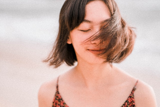 a girl with her eyes closed, hair flying over her face, finding peace through spiritual counseling