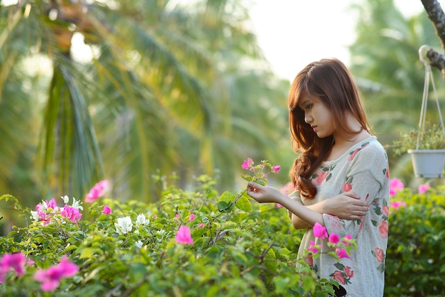 a woman in a beautiful garden holding flowers in her hand feeling emotional spiritual awakening symptoms