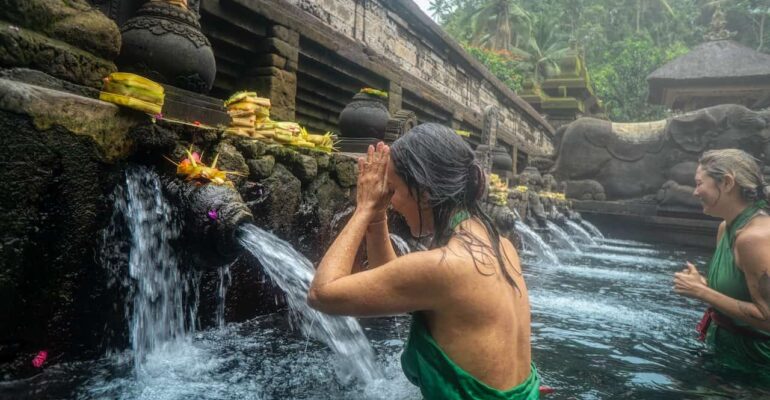 a woman getting purified in Asia in a beautiful spring waterfall for spiritual purification as she navigates through her spiritual awakening stages