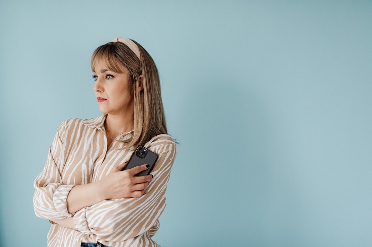 a woman with her phone in her hands staring blankly thinking on how to deal with a narcissist