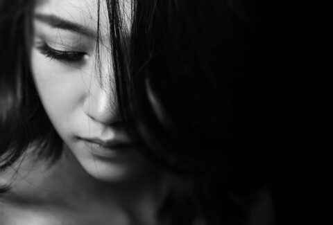 woman's face looking down as she is sad because of the 10 trauma bonding signs with her hair covering half her face