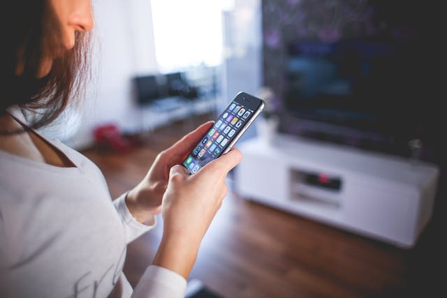 woman staring at her phone while in her living room wondering about the things narcissists do when you go no contact