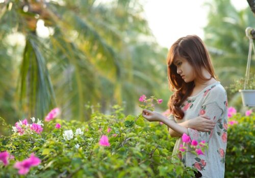 a woman in a garden looking down at flowers depicting low self confidence
