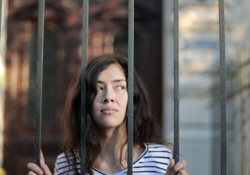 woman behind bars reflecting the effect of trauma bonding due to narcissistic abusive relationships