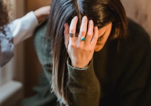 woman showing grief as she looks down and holds her head with her hand